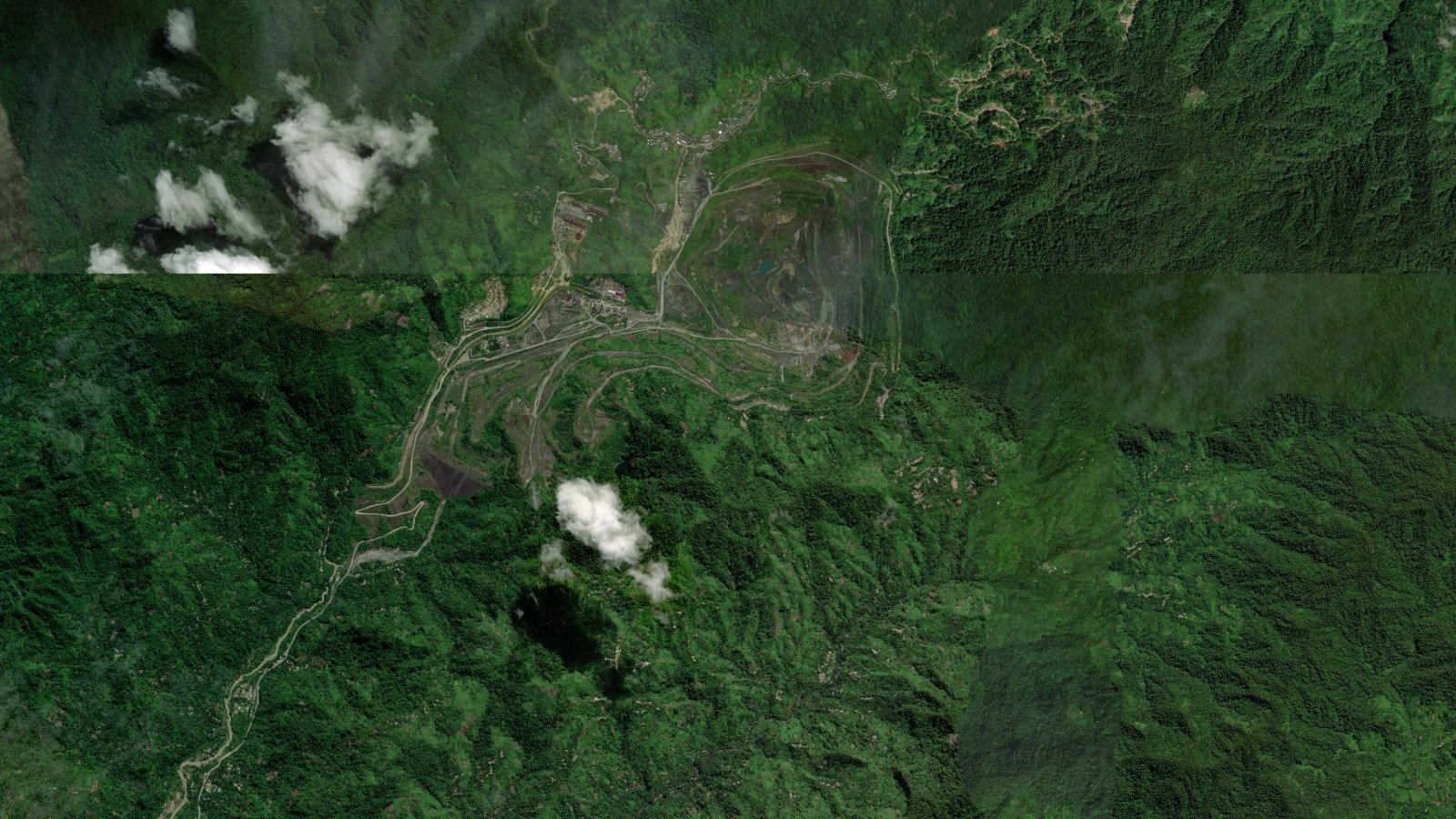 Satellite view of the abandoned Panguna open-pit copper-gold mine in central Bougainville, showing the flooded pit, terraced benches and the tailings-scarred Jaba river valley below.