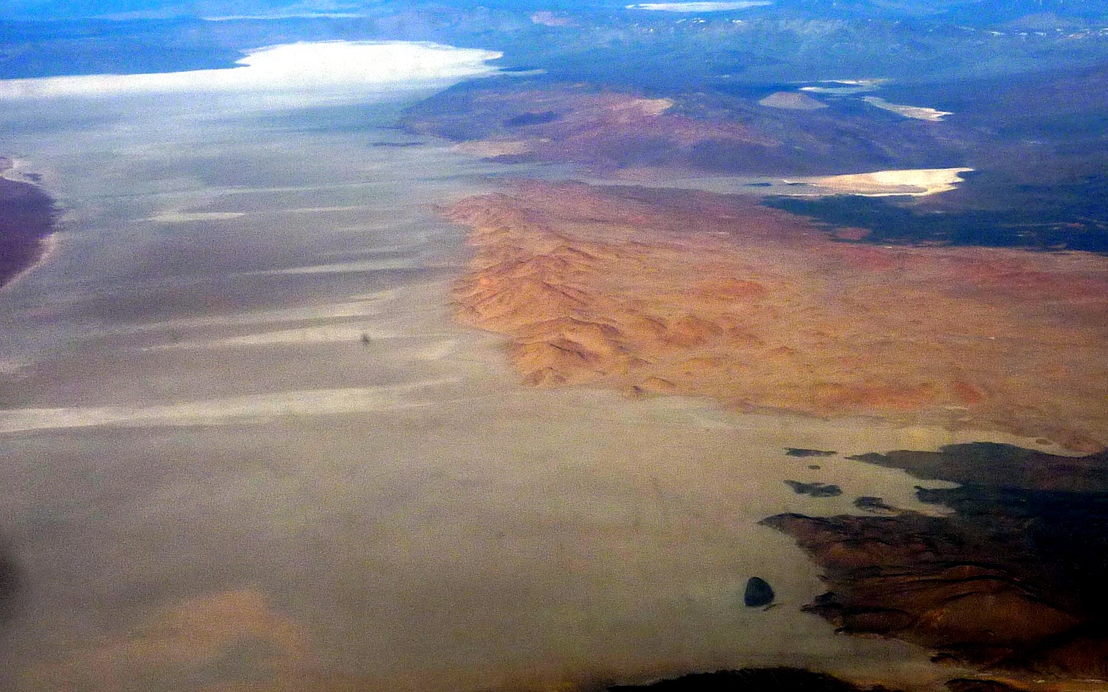 Aerial view of the Salar de Arizaro in Salta province, Argentina, a vast pale salt flat ringed by desert ranges.