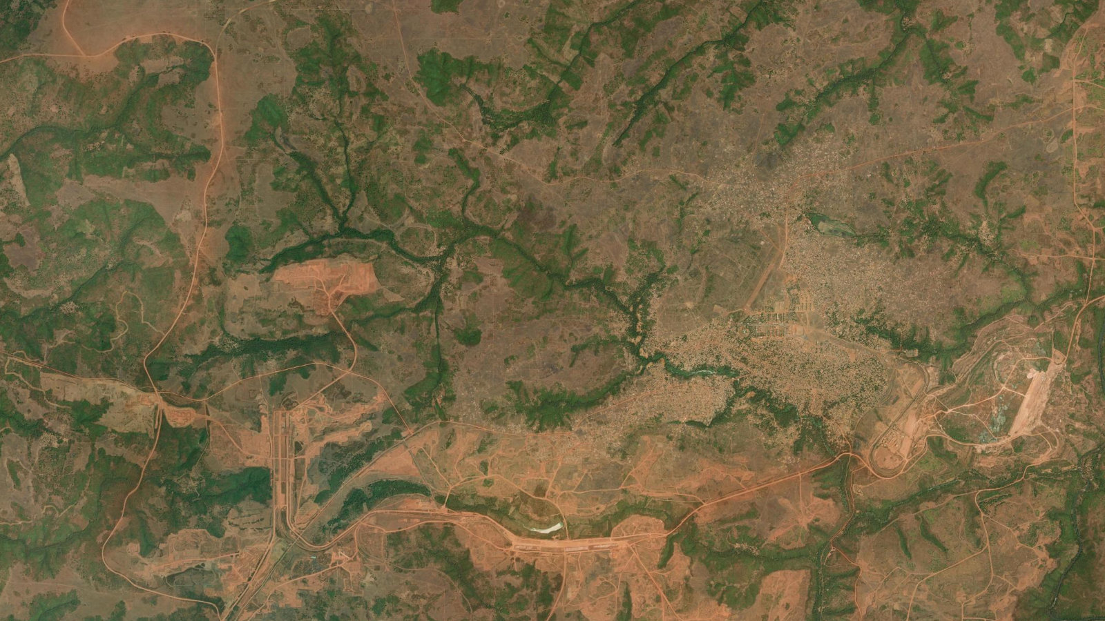 Satellite view of the Sangarédi bauxite district in the Boké region of western Guinea, showing red-laterite open pits, haul roads, rail infrastructure and the town of Sangarédi.